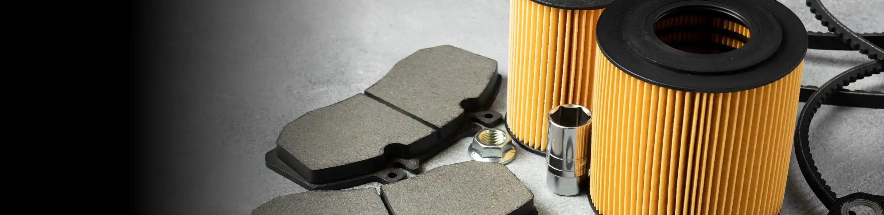 
Automotive filters, brake pads, and hardware parts arranged on a gray surface